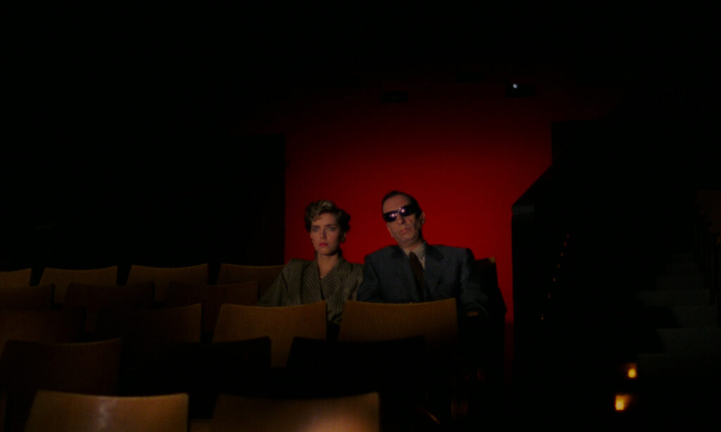 Blind man sitting with his daughter in a movie theatre as the lights go down in Demons