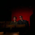 Blind man sitting with his daughter in a movie theatre as the lights go down in Demons