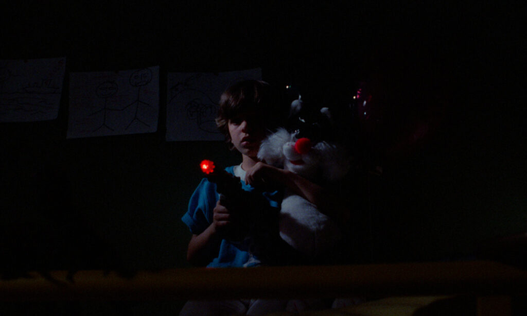 Tommy aiming a laser pistol and clutching his Sylvester the Cat plushie